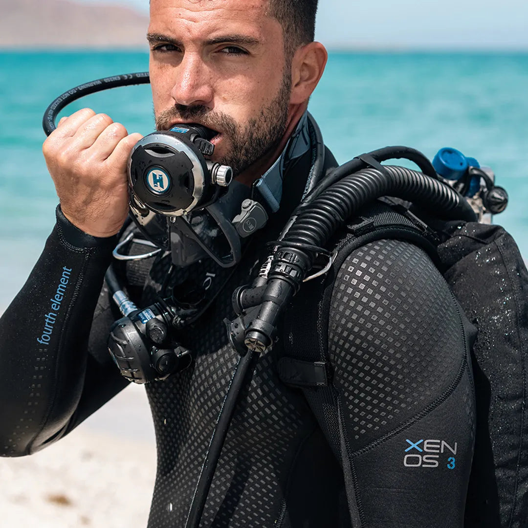 Diver in a Fourth Element Xenos ARC 3mm Wetsuit with scuba gear on a beach