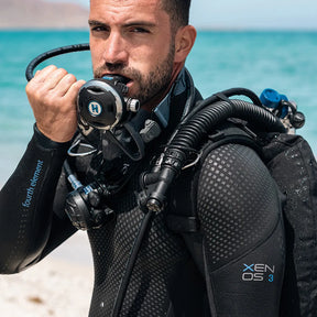 Diver in a Fourth Element Xenos ARC 3mm Wetsuit with scuba gear on a beach